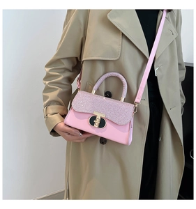Close-up of pink leather handbag featuring a glitter flap and gold metal turn-lock clasp