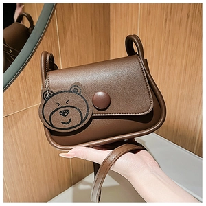 Close-up of brown PU leather bag featuring a large round button and a cute bear charm