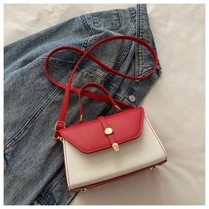 Détail du sac bandoulière rouge et blanc avec boucle dorée sur fond denim