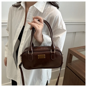 Detail shot of the dark brown retro bowling bag showing the glossy leather texture and gold hardware