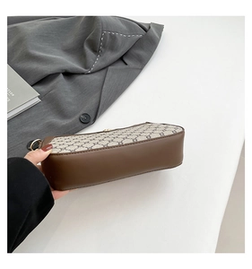 Detail of vintage patterned PU leather underarm bag with gold hardware and brown trim