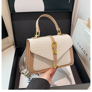 Detail view of woven texture and gold metal buckle on beige crossbody square bag