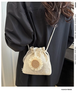Detail of hand-woven straw bucket bag with sunflower decor and drawstring closure
