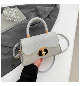 Detail of silver crossbody bag with metallic texture flap and gold T-bar twist lock