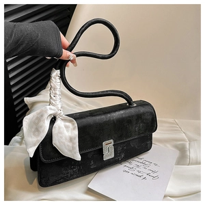 Close-up of black suede shoulder bag with silk scarf detail and diamond S-shaped buckle