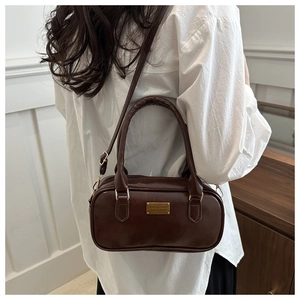 Detail of dark brown leather Boston bag with gold metal plate and dual strap design