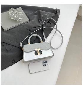 Detail of silver mirror texture and fabric flap with metal buckle shown with a smartphone