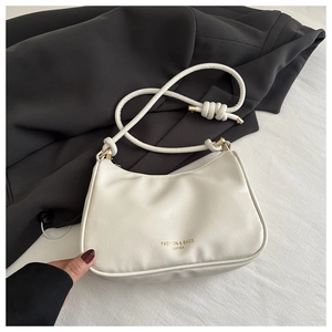 Detail of white leather underarm bag with gold logo lettering on grey suit background