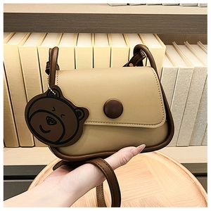 Detail view of mini square crossbody bag with bear pendant and stylish two-tone leather