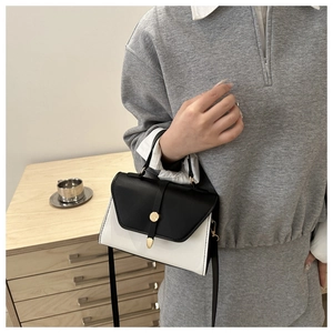 Gros plan d'un sac bandoulière bicolore noir et blanc porté par un mannequin