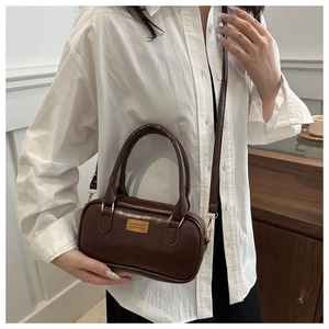 Detail view of dark brown faux leather bowling bag with gold buckle and top handle