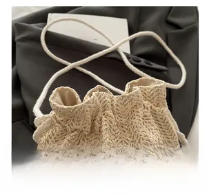 Detail of woven straw bucket bag showing drawstring closure and knit flower accent