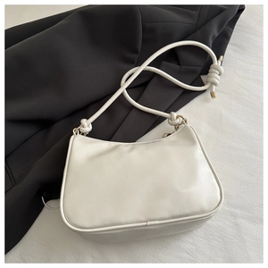 Detail of cream white leather shoulder bag featuring decorative knotted strap and gold hardware