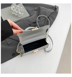 Top view of open silver rectangular handbag showing black lining and crystal handle