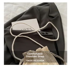 Detail of hand-woven straw bucket bag featuring a soft white braided cotton shoulder strap