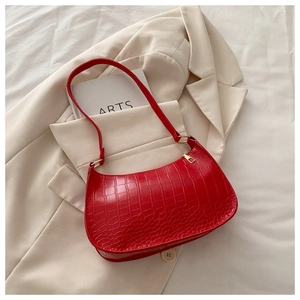 Detail of red crocodile pattern shoulder bag on white blazer showing textured faux leather