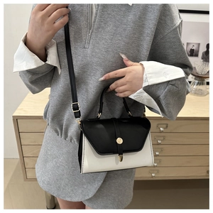 Détail d'un sac bandoulière minimaliste noir et blanc avec boucle dorée sur modèle