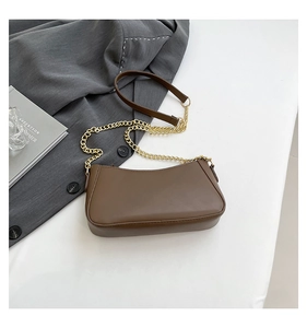 Top view of brown PU leather baguette bag with golden chain strap on a desk