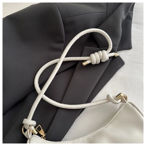 Detail of white PU leather shoulder bag with tubular knotted strap and gold hardware