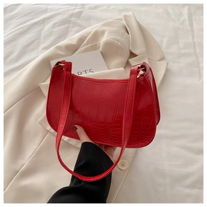 Close-up of red crocodile pattern shoulder bag with polished gold metallic hardware buckle