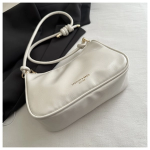Close-up of white faux leather shoulder bag featuring gold hardware and knot details