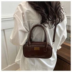 Model view of coffee brown PU leather bowling bag with gold logo and crossbody strap