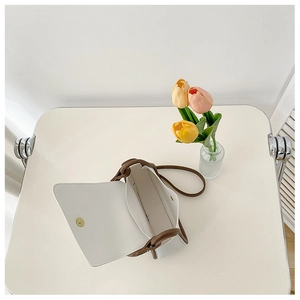 Interior view of cream minimalist flap bag with brown trim and magnetic closure