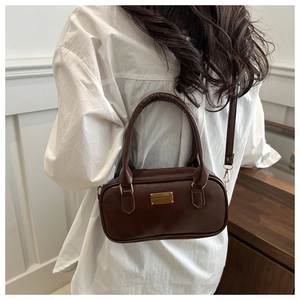 Detail of dark brown matte faux leather handbag with golden metal plate and top handle