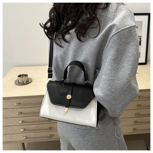 Sac bandoulière bicolore chic avec boucle dorée porté à l'épaule pour un look quotidien