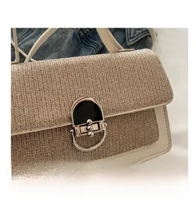 Detail of elegant cream fabric crossbody bag featuring a golden metallic oval clasp