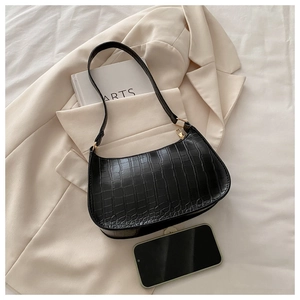 Detail of black crocodile texture shoulder bag with gold hardware on aesthetic background