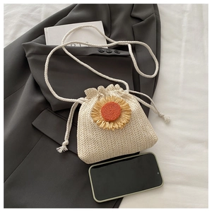 Detail of woven straw bucket bag with sunflower accent and smartphone for size reference