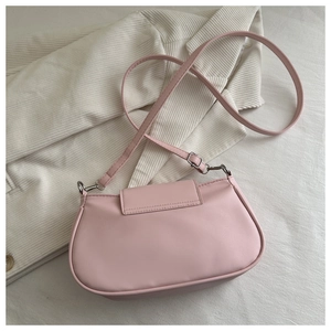 Detail of pink semi-circular matte leather crossbody bag on white corduroy background