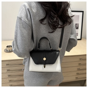 Détail d'un mini sac à bandoulière noir et blanc avec boucle dorée porté par un mannequin