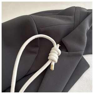 Close-up of white lychee pattern leather strap with gold metal caps and knotted design