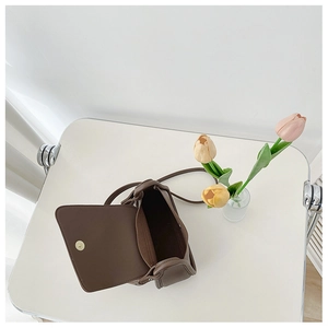 Detail view of the brown leather crossbody bag showing inner space and magnetic buckle