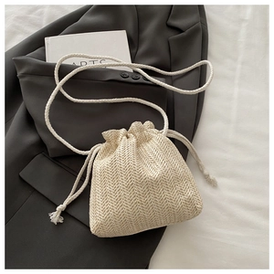 Détail du sac seau en paille beige avec texture chevrons et cordon de serrage en coton