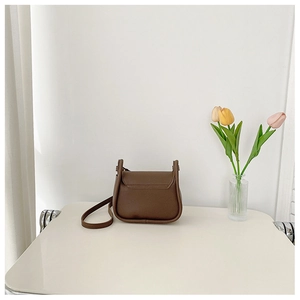 Minimalist dark brown leather square bag shown with a tulip vase on a light tabletop