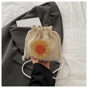 Vue détaillée du sac seau en paille tissée avec tournesol 3D et cordon de serrage