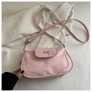 Detail of light pink saddle bag featuring silver metal bow and decorative stitching