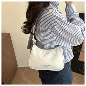 Detail of white glossy leather underarm bag with metal buckle and fashion lettering