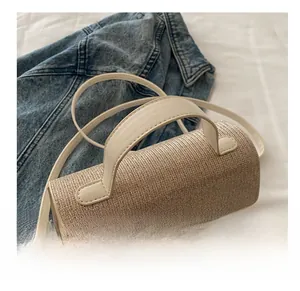 Detailed close-up of woven beige square handbag with leather strap and metal clasp