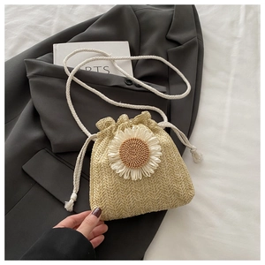 Détail du sac seau en paille avec une grande fleur 3D et une bandoulière en coton tressé