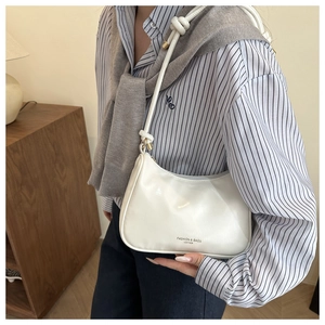 Detail of white leather shoulder bag with knotted strap and minimalist logo on stripe shirt