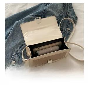 Interior view showing capacity of off-white woven shoulder bag with a phone and wallet