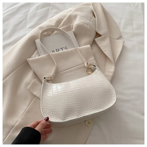 Detail of white crocodile pattern underarm bag with golden zipper and leather strap