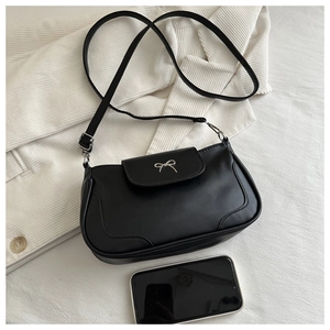 Detail of black vintage shoulder bag with silver bow accent and adjustable strap