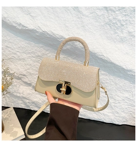 Detail of elegant cream handbag with sparkling rhinestone handle and gold metal twist lock