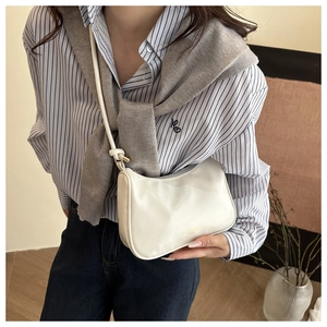 Detail of minimalist cream leather underarm bag featuring gold lettering and adjustable strap