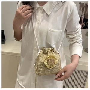 Detail of woven straw bucket bag featuring a bright sunflower motif and drawstring cord